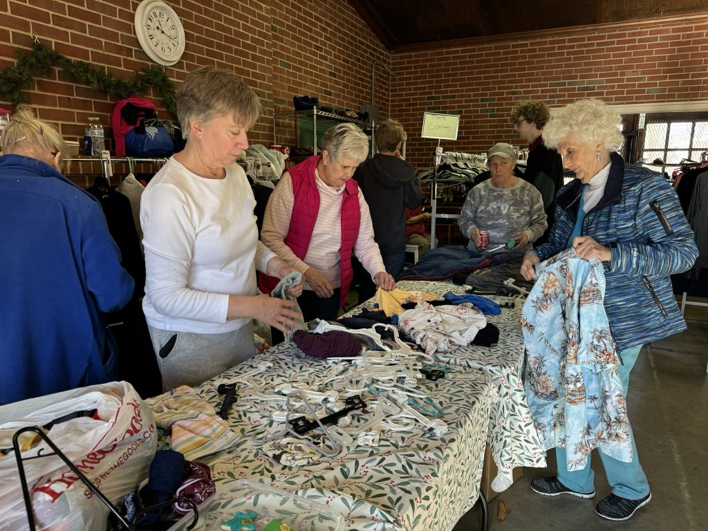 volunteers around a table sort clothing to be given away