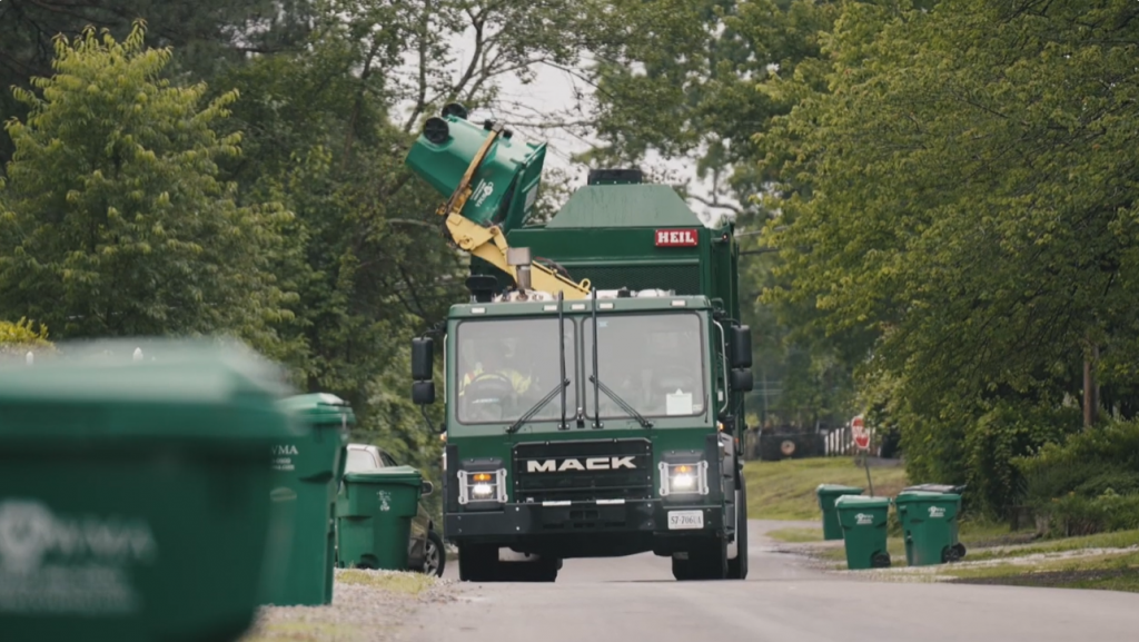 a recycling truck empties a recycling cart on a suburban street